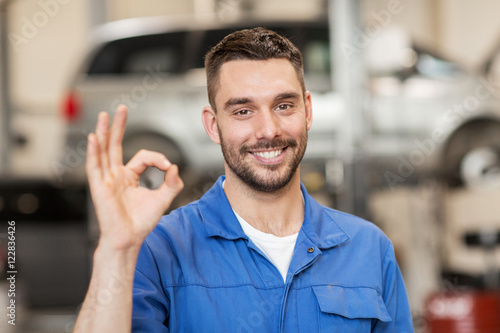 Fototapeta auto mechanic or smith showing ok at car workshop