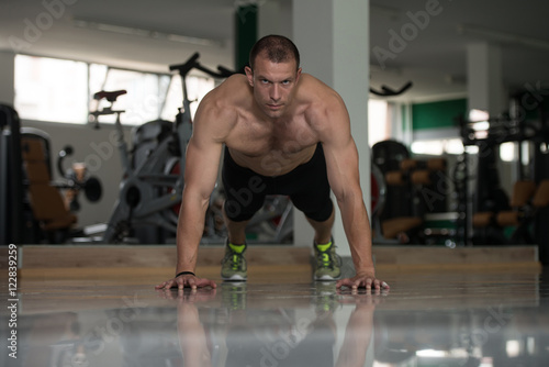 Fototapeta Naklejka Na Ścianę i Meble -  Bodybuilder Doing Push Ups On Floor