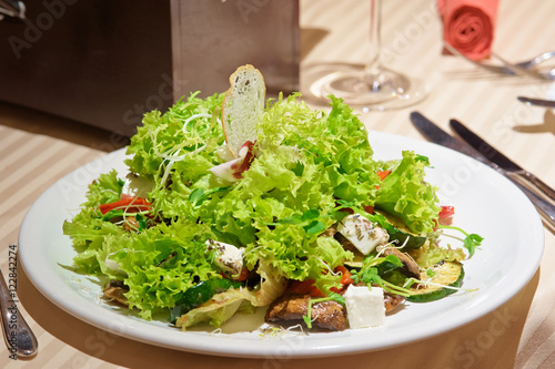 Salad with grilled meat and vegetables and fetta cheese on restaurant table