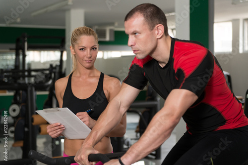 Gym Coach Helping Woman On Bicycle