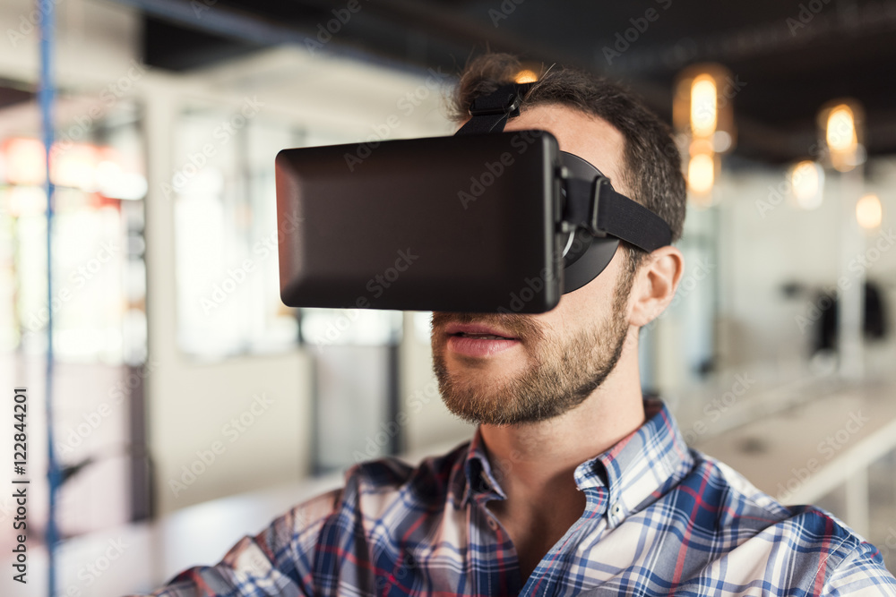 Portrait of man using virtual reality glasses in startup office. Portrait of man using virtual reality glasses in startup office.