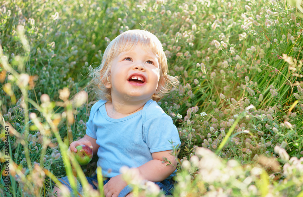 Happy childhood. Little boy with apple plays on a green meadow. Happy childhood. Little boy with apple plays on a green meadow.