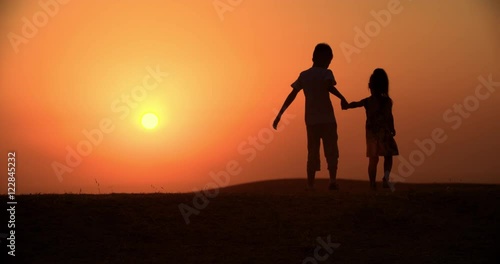 Wallpaper Mural silhouette of two children, a brother and sister walking holding hands, slow motion Torontodigital.ca