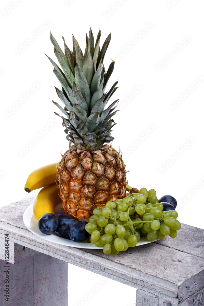 Fruits on the wooden table. Bananas, plums, pineapple, grapes on Fruits on the wooden table. Bananas, plums, pineapple, grapes on