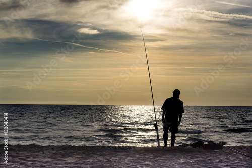 silhouette of fishermen at sunset on the sea beach
