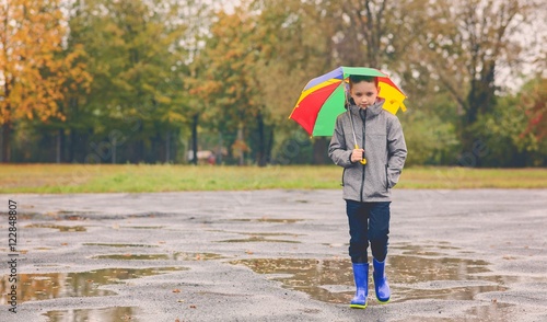 Obraz na płótnie Sad child walking in rubber wellingtons on wet footpath. w salonie
