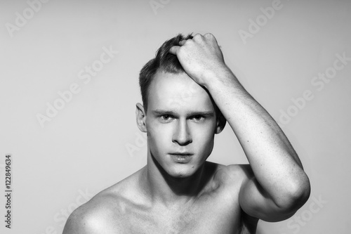 Studio fashion style closeup face portrait of young emotional man holding his red hair with his hand