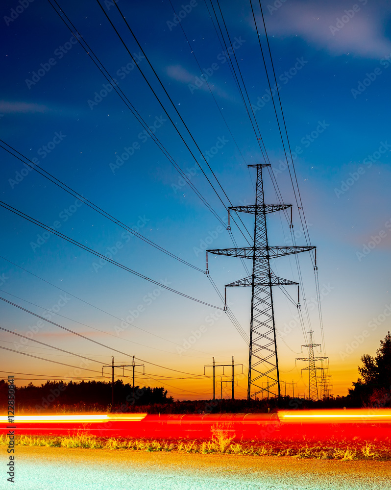 Silhouettes high voltage electric pylon in sunset background