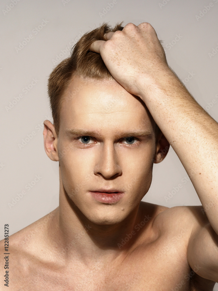Studio fashion style closeup face portrait of young emotional man holding his red hair with his hand Studio fashion style closeup face portrait of young emotional man holding his red hair with his hand