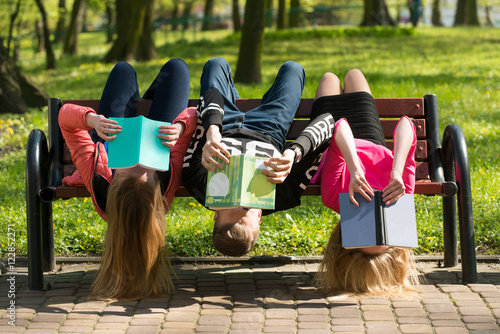 Młodzież czyta książki w parku na ławce