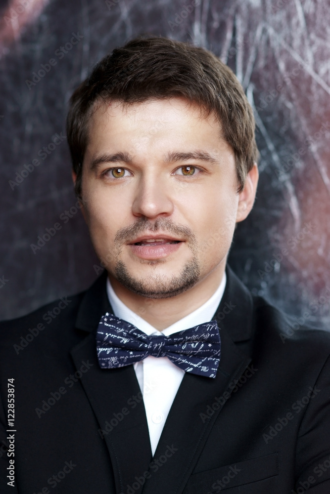 Closeup face portrait of young handsome stylish man in black formal suit posing and looking at you Closeup face portrait of young handsome stylish man in black formal suit posing and looking at you