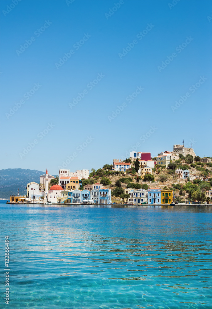 View over bay of Kastelorizo. Island coast with typical colorful Greek houses and clear turquoise sea water. Dodecanese, Greece