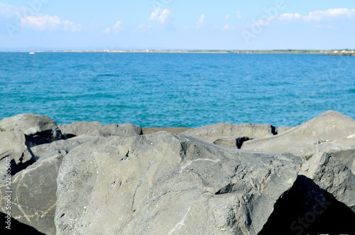 scogli neri, cielo blu e mare