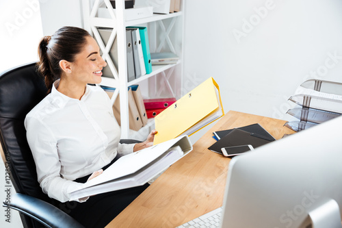 Businesswoman holding yellow binders at office