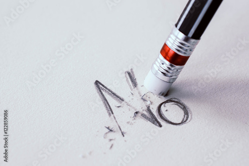 Photography pencil erasing the word No on paper.