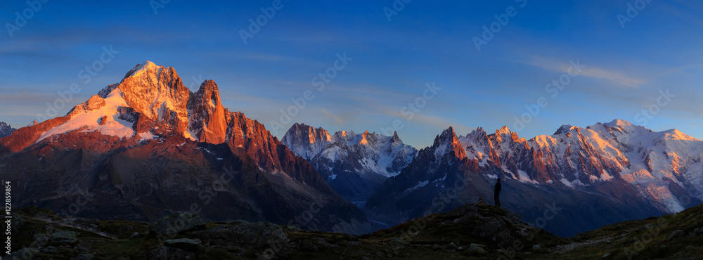 Man enjoying the view of the Alps, with Aiguille Verte and Les Drus, near Chamonix during sunset.