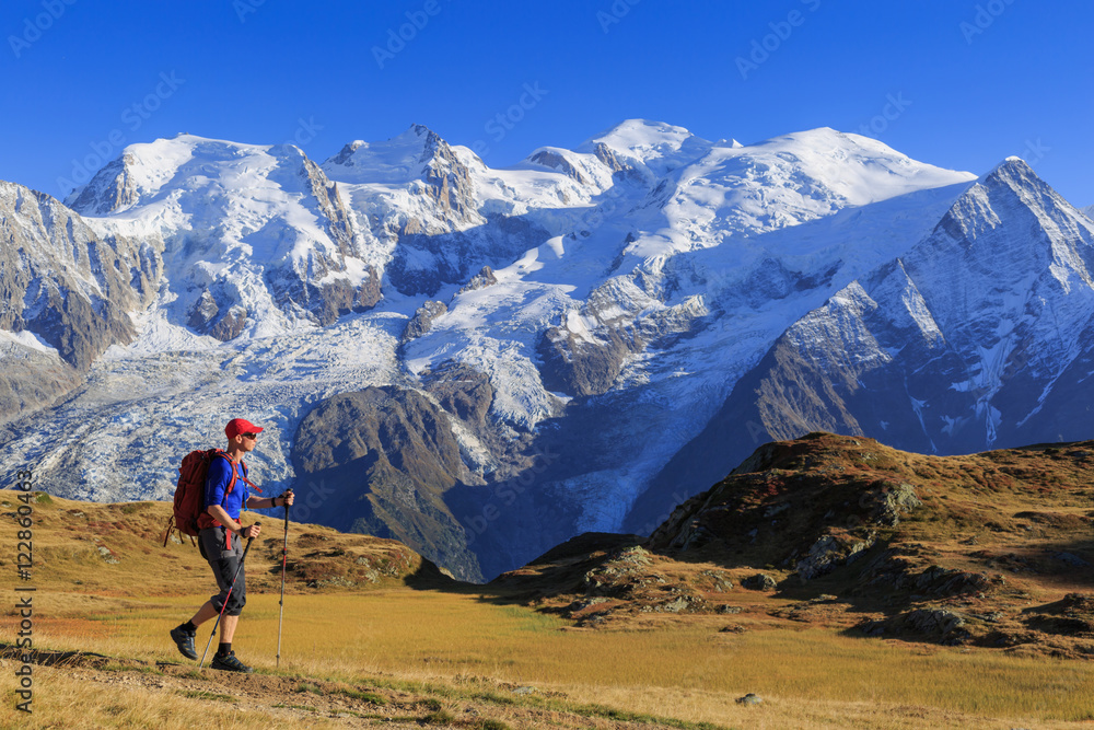 Hiker in a meadow and the famous Mont Blanc. Chamonix, France.