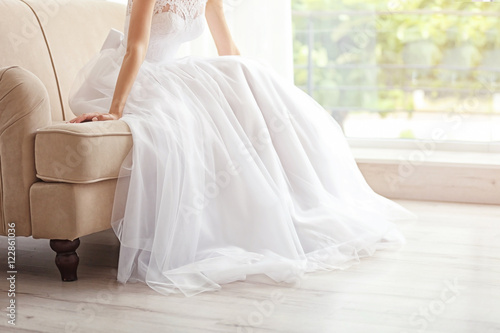 Bride in beautiful wedding gown sitting on sofa © Africa Studio