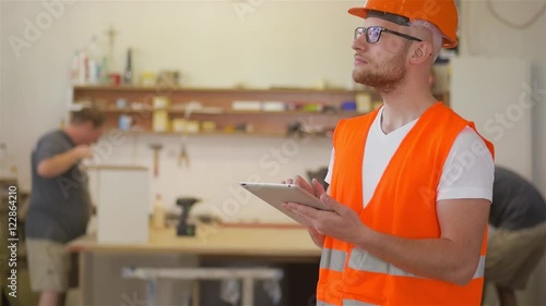Carpenter is using tablet pc in caprentry shop.