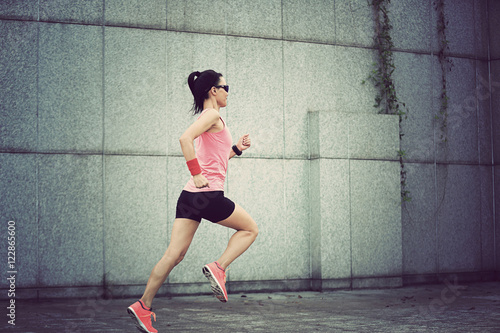 young fitness sport woman running against wall on city