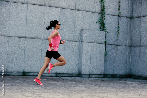 young fitness sport woman running against wall on city