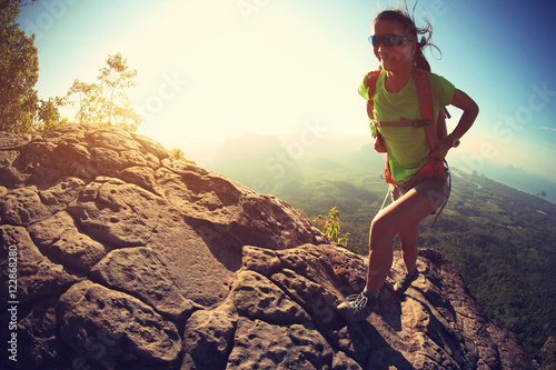 successful woman hiker climbing rock on mountain peak cliff