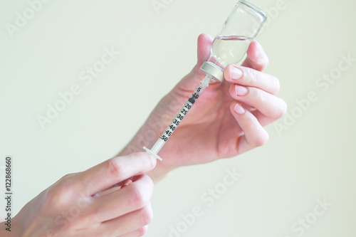 Nurse is  drawing  solution into syringe from vial for preparing