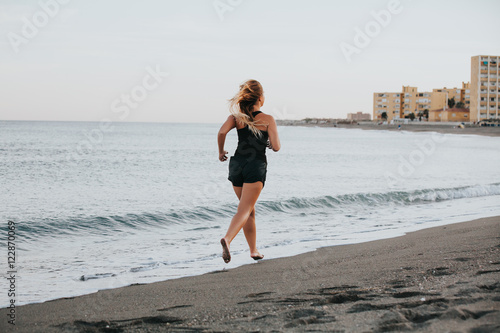 Blonde woman running barefoot on the beach. © daviles