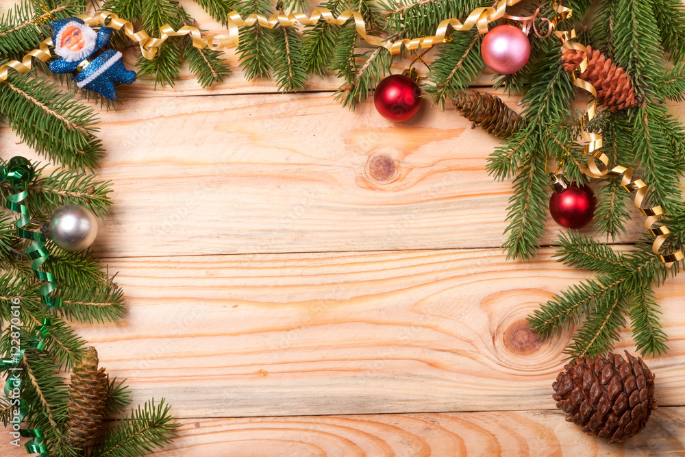 frame of fir branches with Christmas decorations on a light wooden background frame of fir branches with Christmas decorations on a light wooden background