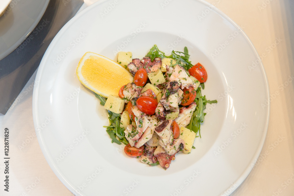 Tasty salad decorated with orange lie on a white plate Tasty salad decorated with orange lie on a white plate