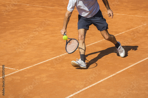 Male tennis player in action on the clay court on a sunny day © smuki