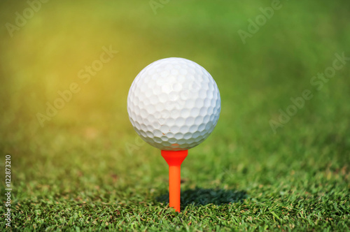close up golf ball with tee on green grass 