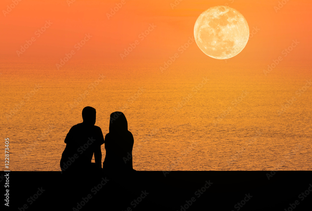 silhoutte rear view romantic couple sit relaxing on the beach in sunset  with full moon 