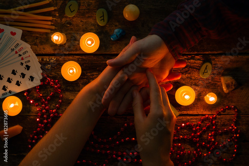 fortuneteller reads fortunes by hand on a background of candles and runes