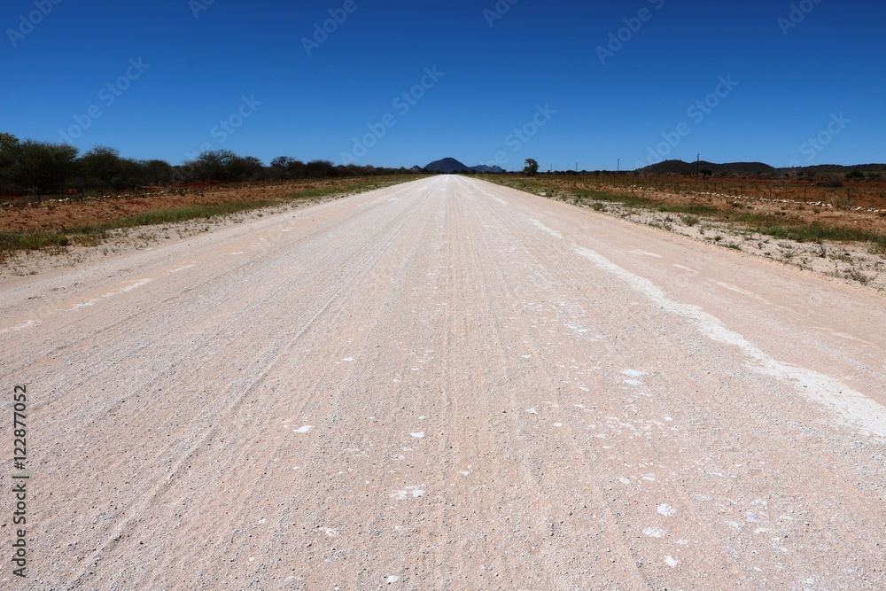 Naklejka premium Dusty dirt road in Namibia under blue sky, Africa