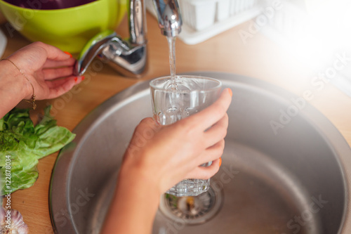 Woman hand's filling the glass of water