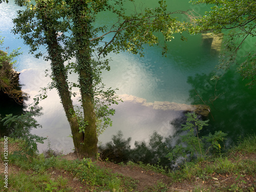 Turquoise lake with sky reflection and trees. Unspoiled nature.