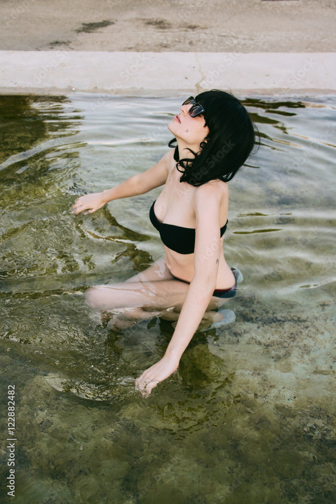 Mujer joven y elegante bañándose en una piscina natural con un bikini negro  Stock-Foto | Adobe Stock