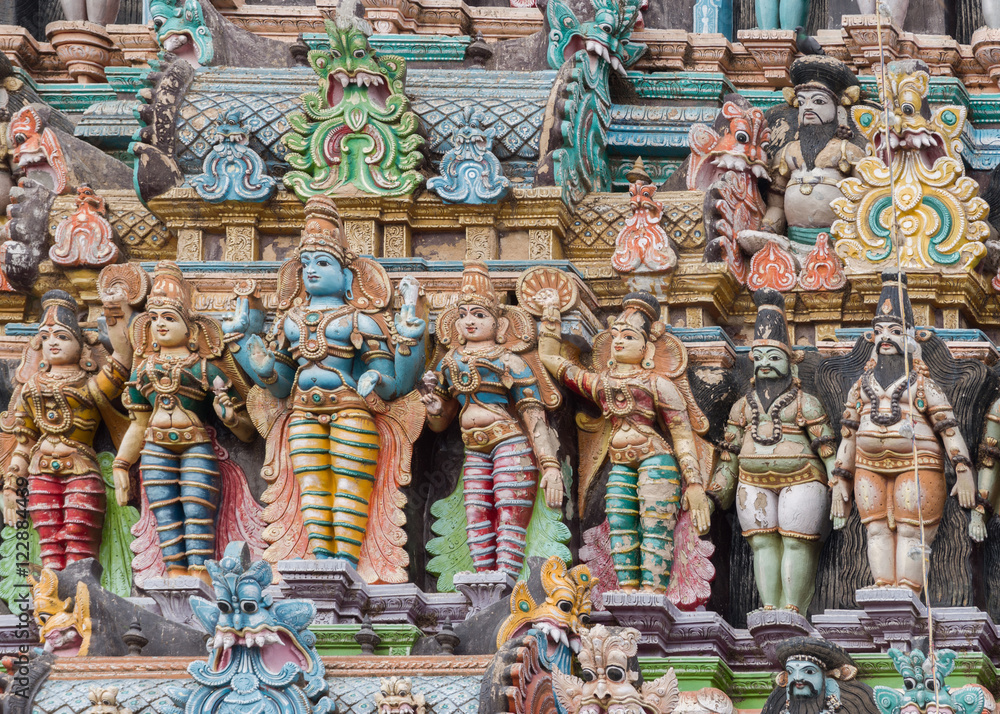 Madurai, India - October 19, 2013: Closeup of Lord Vishnu with his two wives, Lakshmi and Bhu. One servant on each side. Few other figures. Facade of the South Gopuram at Meenakshi Temple. Madurai, India - October 19, 2013: Closeup of Lord Vishnu with his two wives, Lakshmi and Bhu. One servant on each side. Few other figures. Facade of the South Gopuram at Meenakshi Temple.