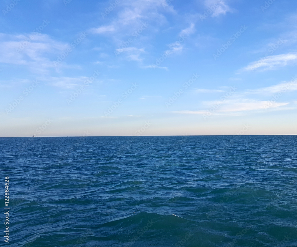 Blue Ocean Water Meets Blue Sky With Clouds