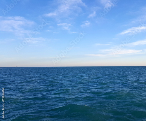 Blue Ocean Water Meets Blue Sky With Clouds