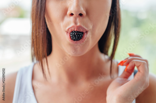 Woman is holding a blackberry in mouth.