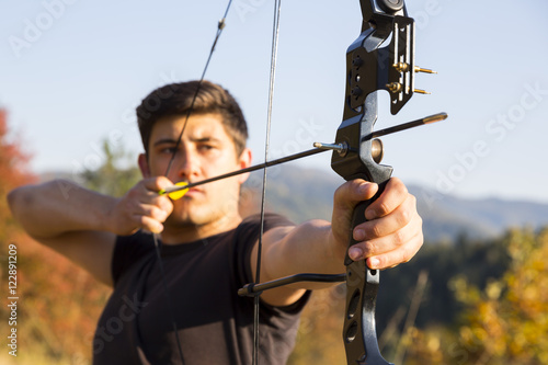 Archer drawing his compound bow trees