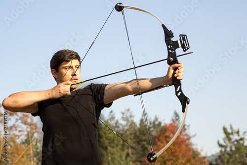 Archer drawing his compound bow trees