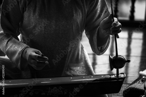 Woman play a typical vietnamese monochord musical instrument : the " dan bau " . Black and white picture