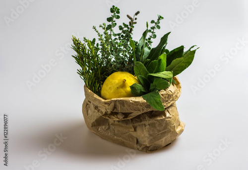 Aromatic herbs and lemon in a bag on a white background