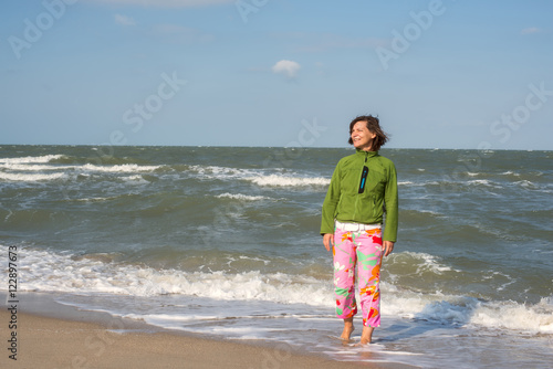 Smiling woman is walking on surf line