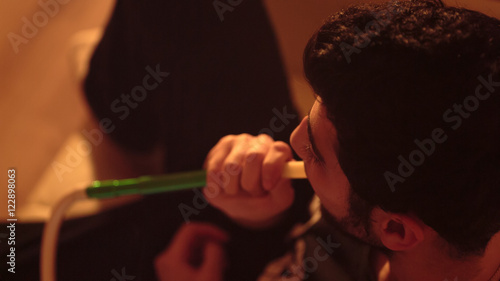 young bearded man smokes a hookah closeup photo