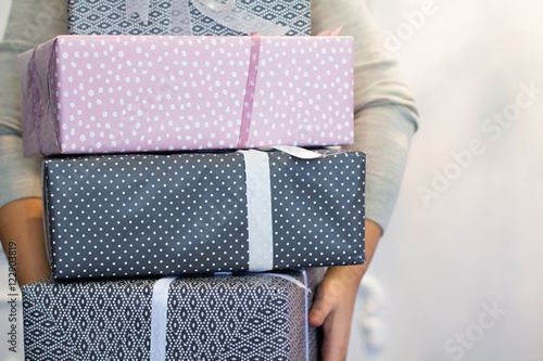 Many gift boxes in the hands of young brunette woman indoors. Ho