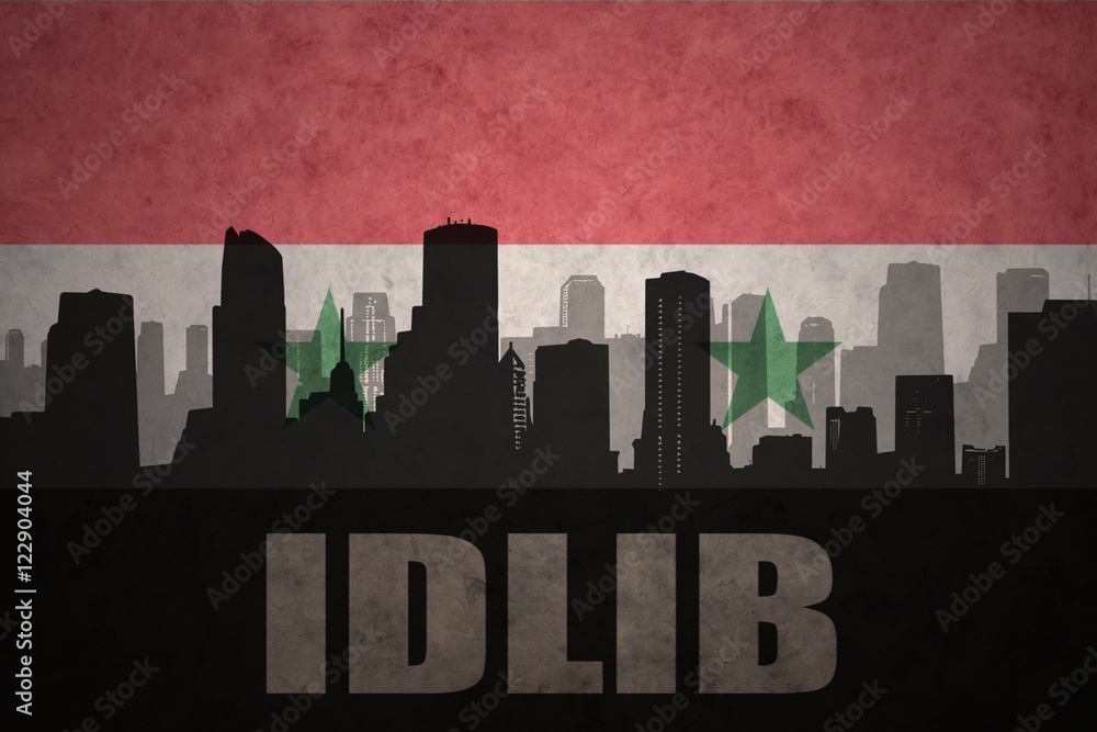 Naklejka premium abstract silhouette of the city with text Idlib at the vintage syrian flag background